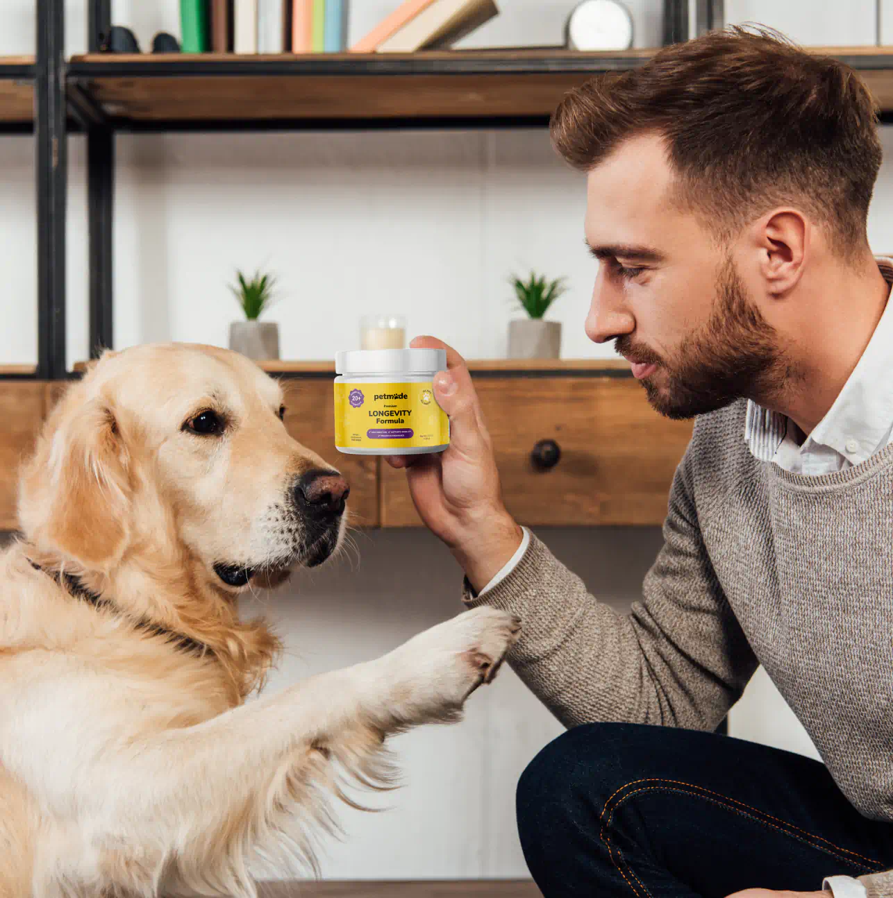A man showing the product to a golden retriever
