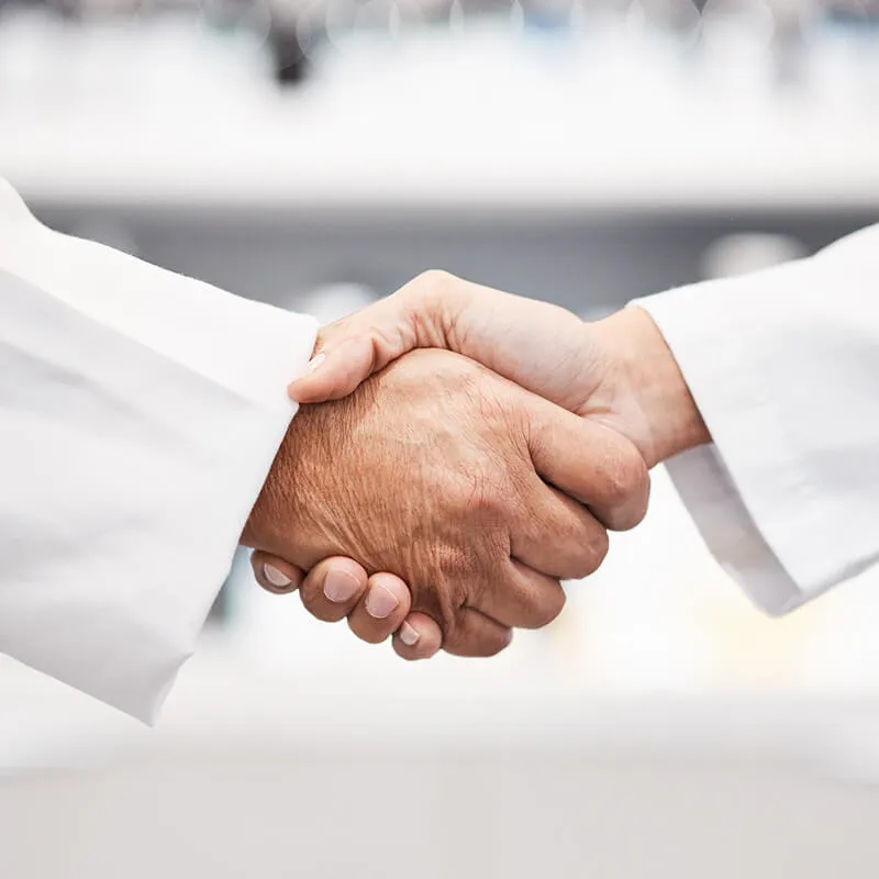 Two people in lab coats shaking hands